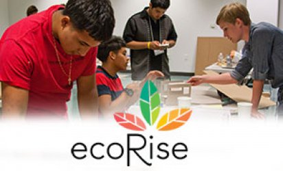 Four students working on models. A boy in a red shirt at the foreground, more prominent than the other three. A white-feathered backdrop covers the lower third with the ecoRise logo at its center: a large R rising at the center of the logo just below three leaves ranging from mutlipe shades of red, to green, to yellow, to orange, in a gradual transition from one leaf to the next over the course of all three leaves. All the leaves radiate out from the dot above the 'i' of Rise.