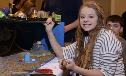 On the right, long haired girl, posing and smiling while displaying her city model on the left.