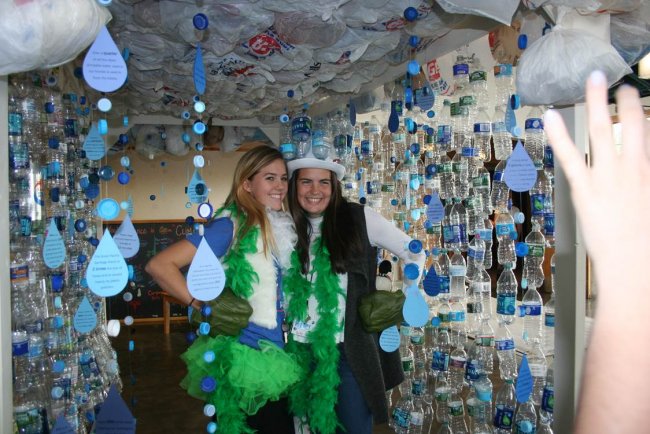 Youth Summit participants pose in an art installation made of recycled plastic bottles, construction paper rain drops, and plastic bags.